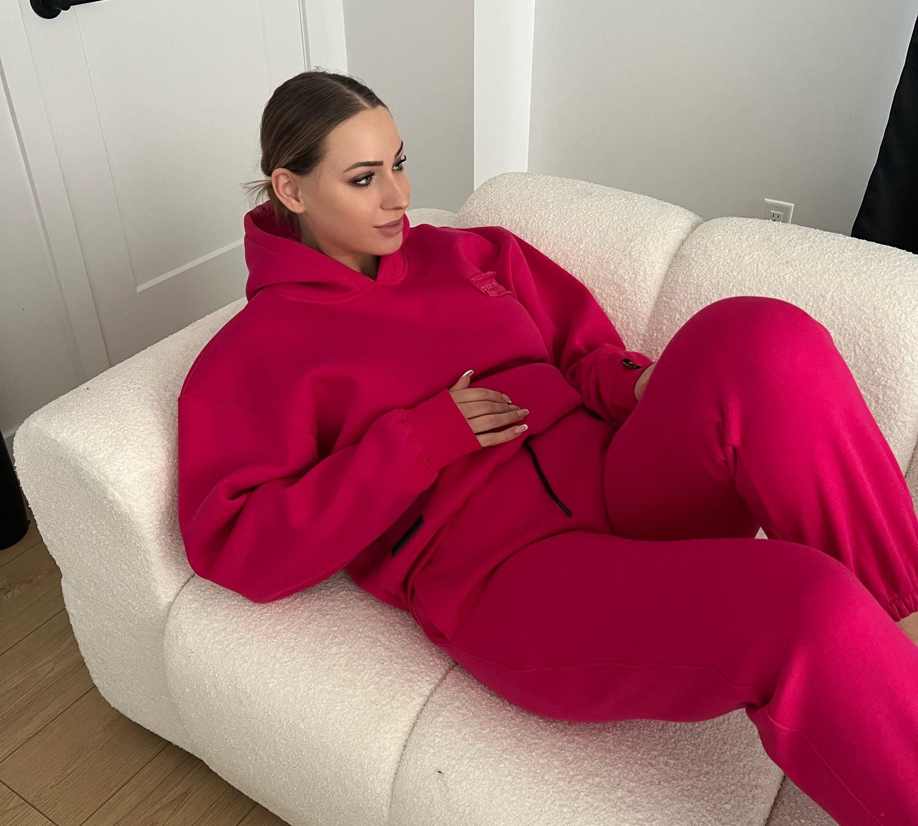 Woman lounging on a sofa in the Dope Beyond Hot Pink hoodie and joggers set