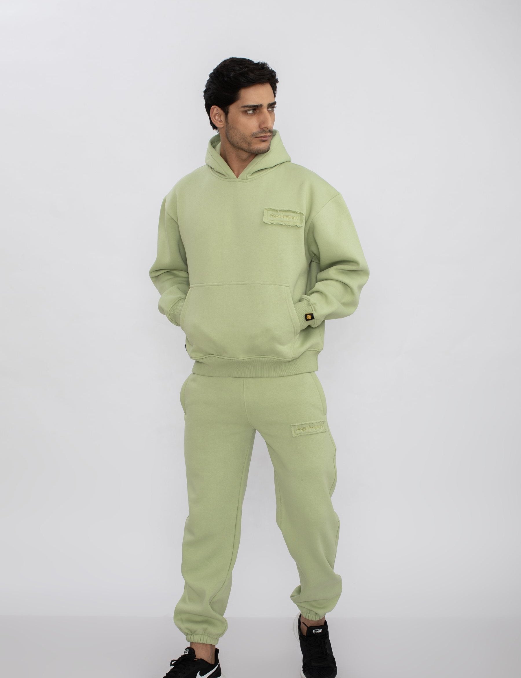 Man in the Dope Beyond Mint Green hoodie and joggers set, hands in pockets, studio