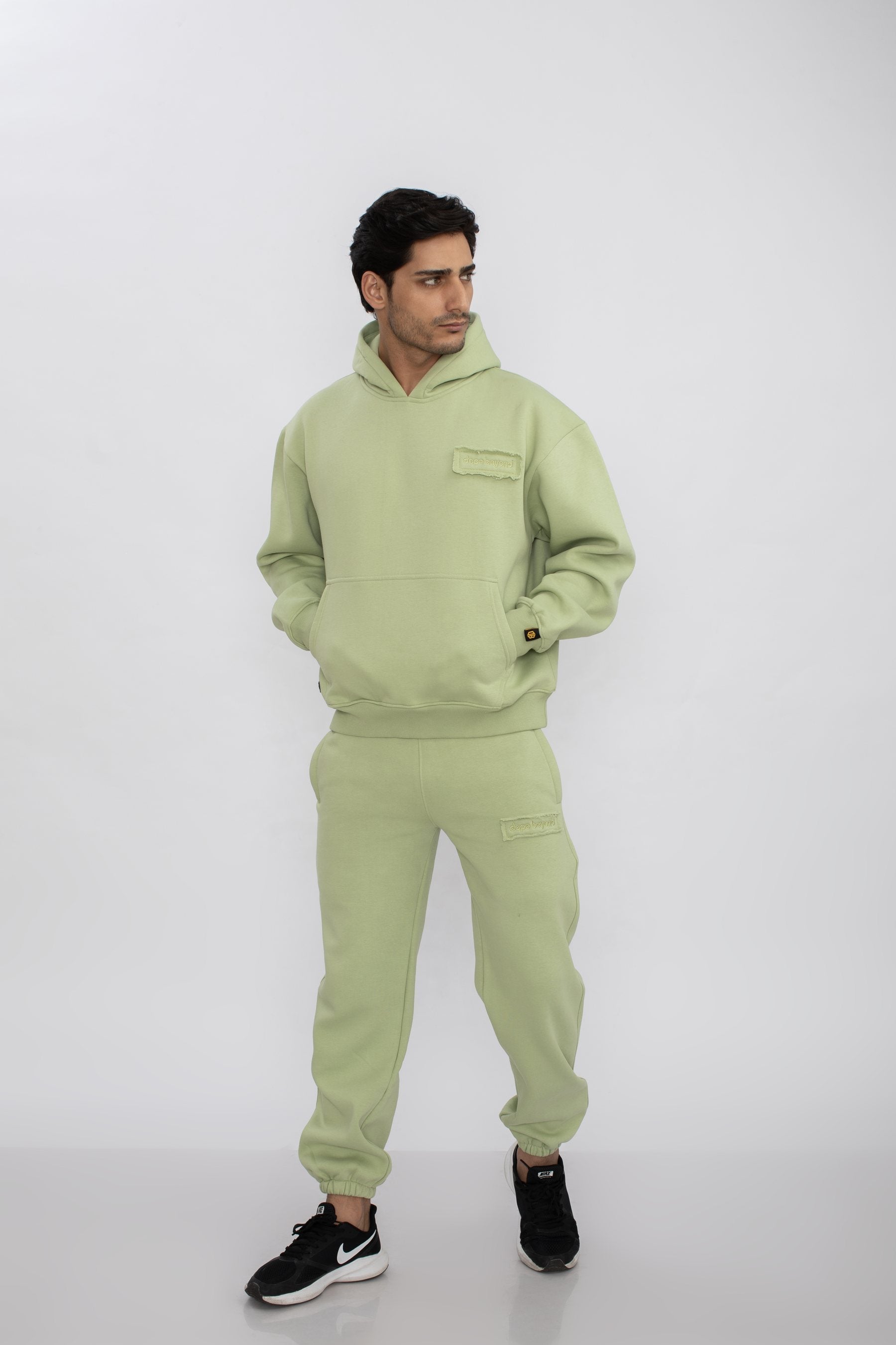 Man in the Dope Beyond Mint Green hoodie and joggers set, hands in pockets, studio