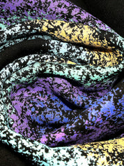 Close-up of multicolored abstract streetwear fabric, featuring vibrant purple, blue, yellow, and black patterns.