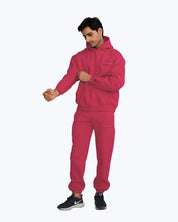 Man in vibrant pink dopebeyond streetwear hoodie and joggers, adjusting sleeve