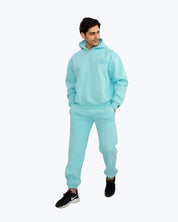 Man wearing light blue dopebeyond streetwear hoodie and joggers set on white background