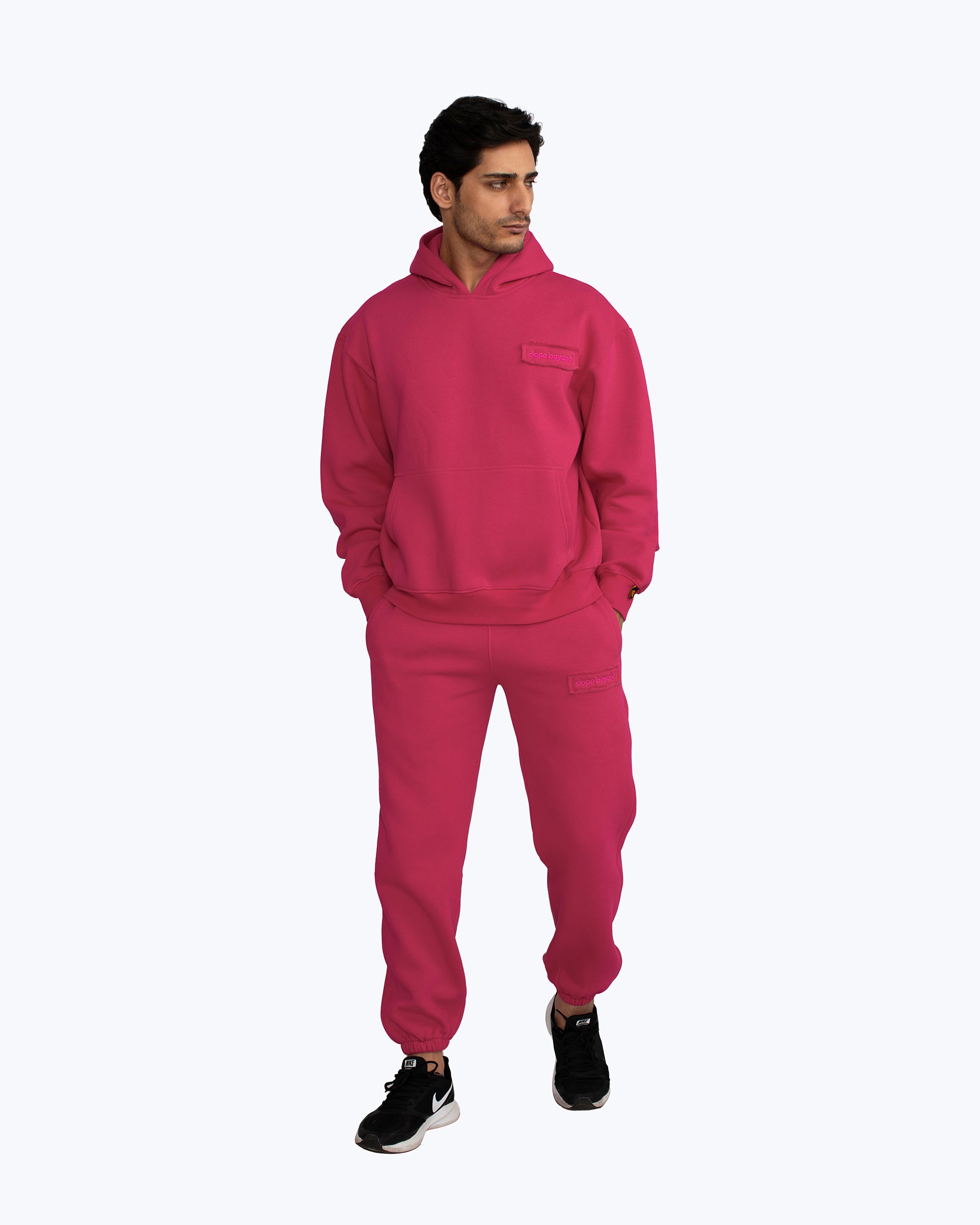 Man wearing dopebeyond magenta streetwear hoodie and sweatpants set on white background