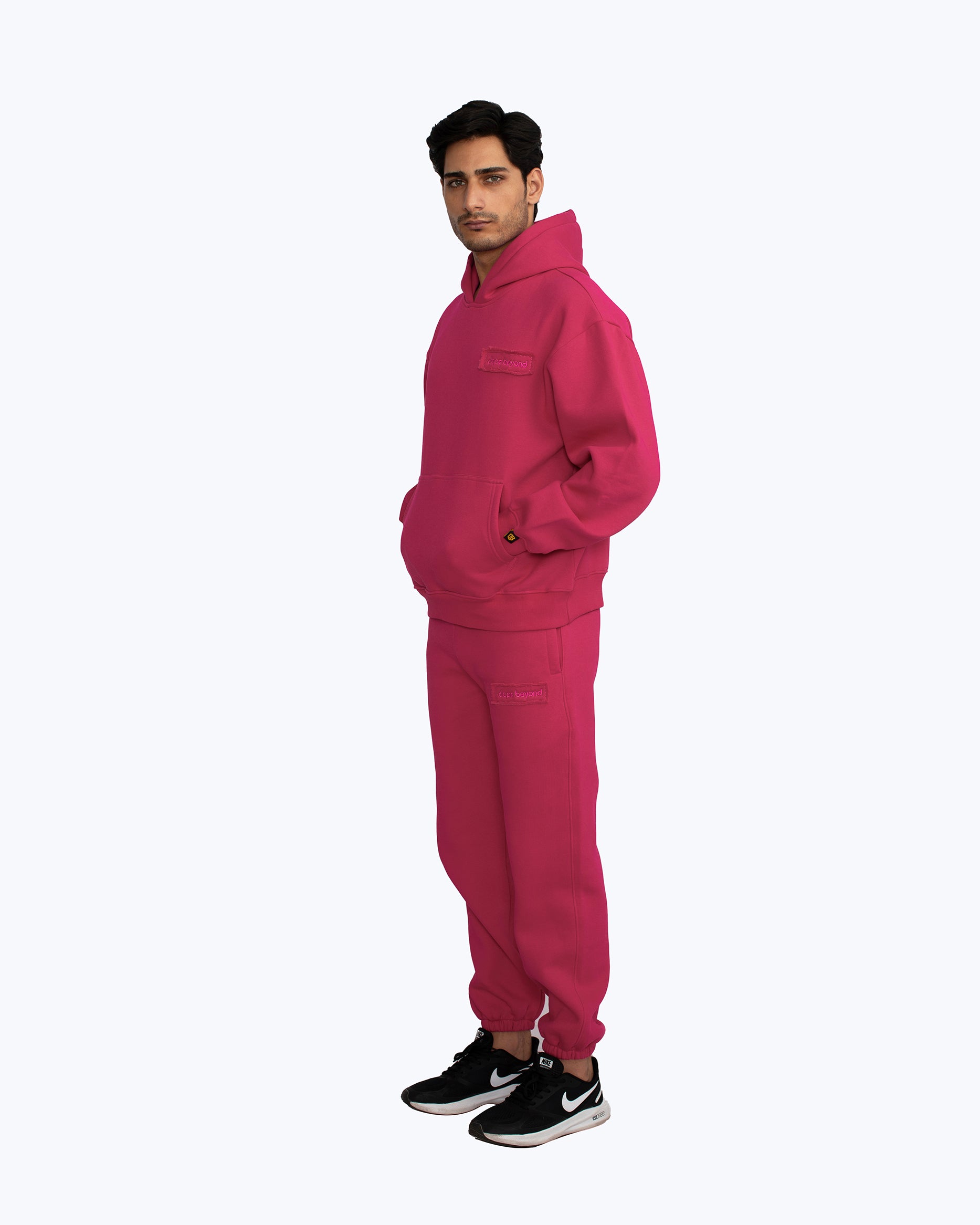 Man modeling dopebeyond pink streetwear hoodie and sweatpants set on white background