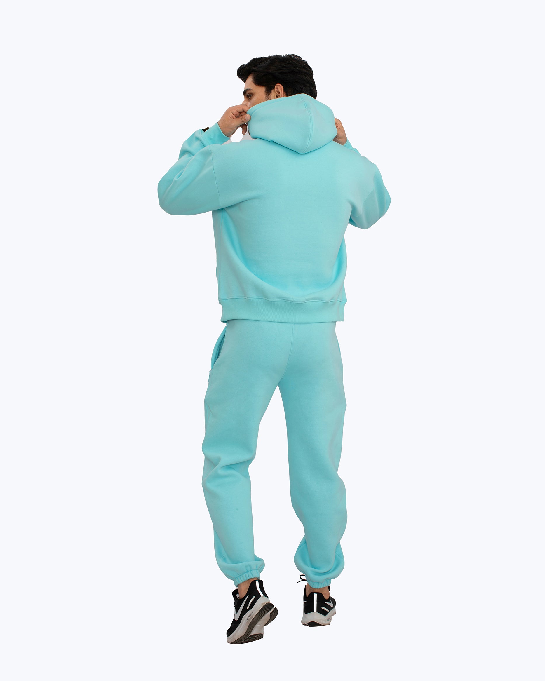Man wearing turquoise streetwear hoodie and joggers set from dopebeyond, rear view