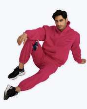 Man in vibrant pink dopebeyond hoodie and joggers, black Nike sneakers, streetwear look