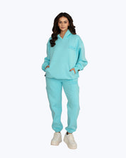Woman wearing light blue dopebeyond streetwear hoodie and joggers set with white sneakers