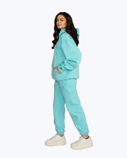 Woman in turquoise dopebeyond streetwear hoodie and joggers with white sneakers