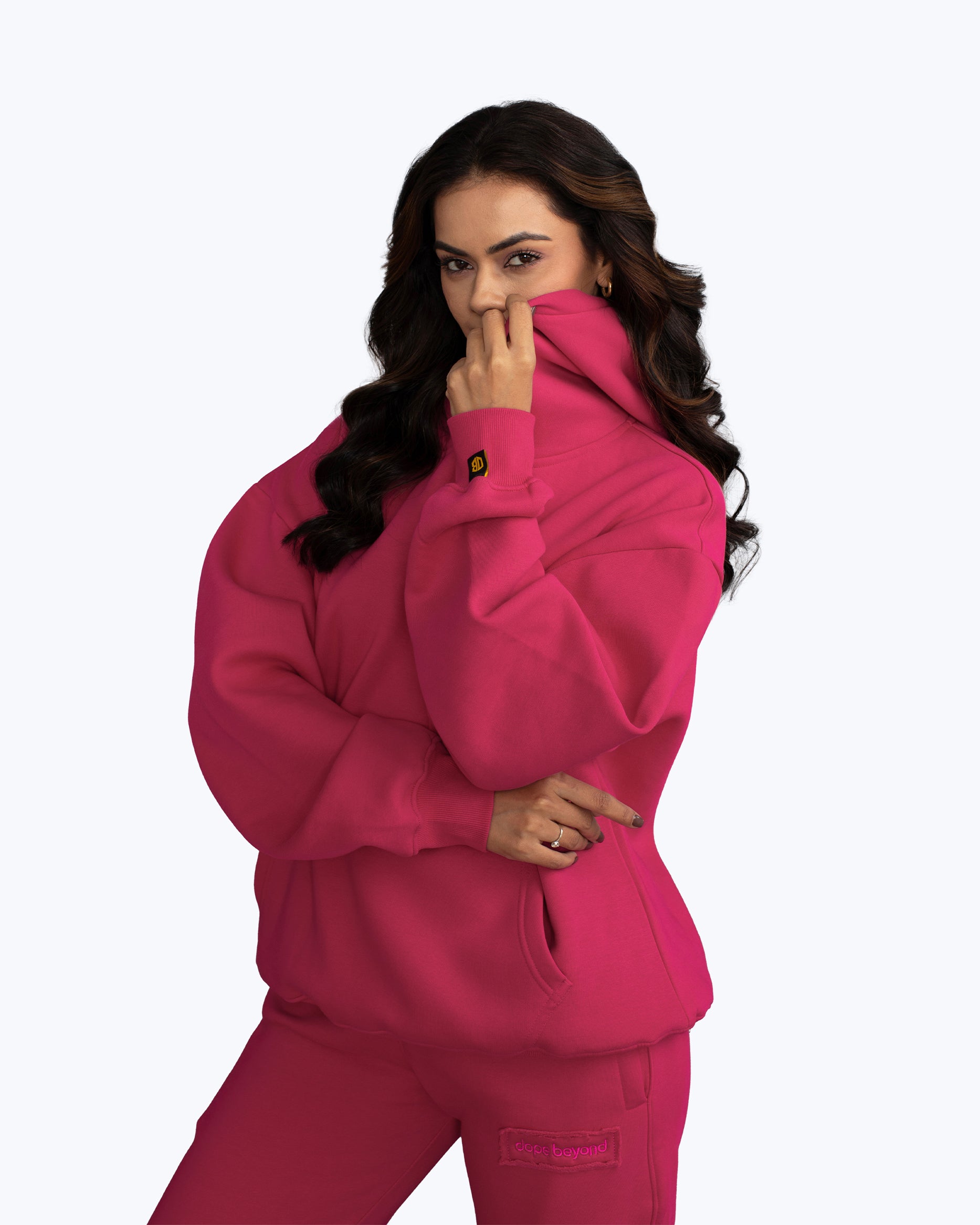 Woman wearing bright pink dopebeyond streetwear hoodie and sweatpants, logo visible