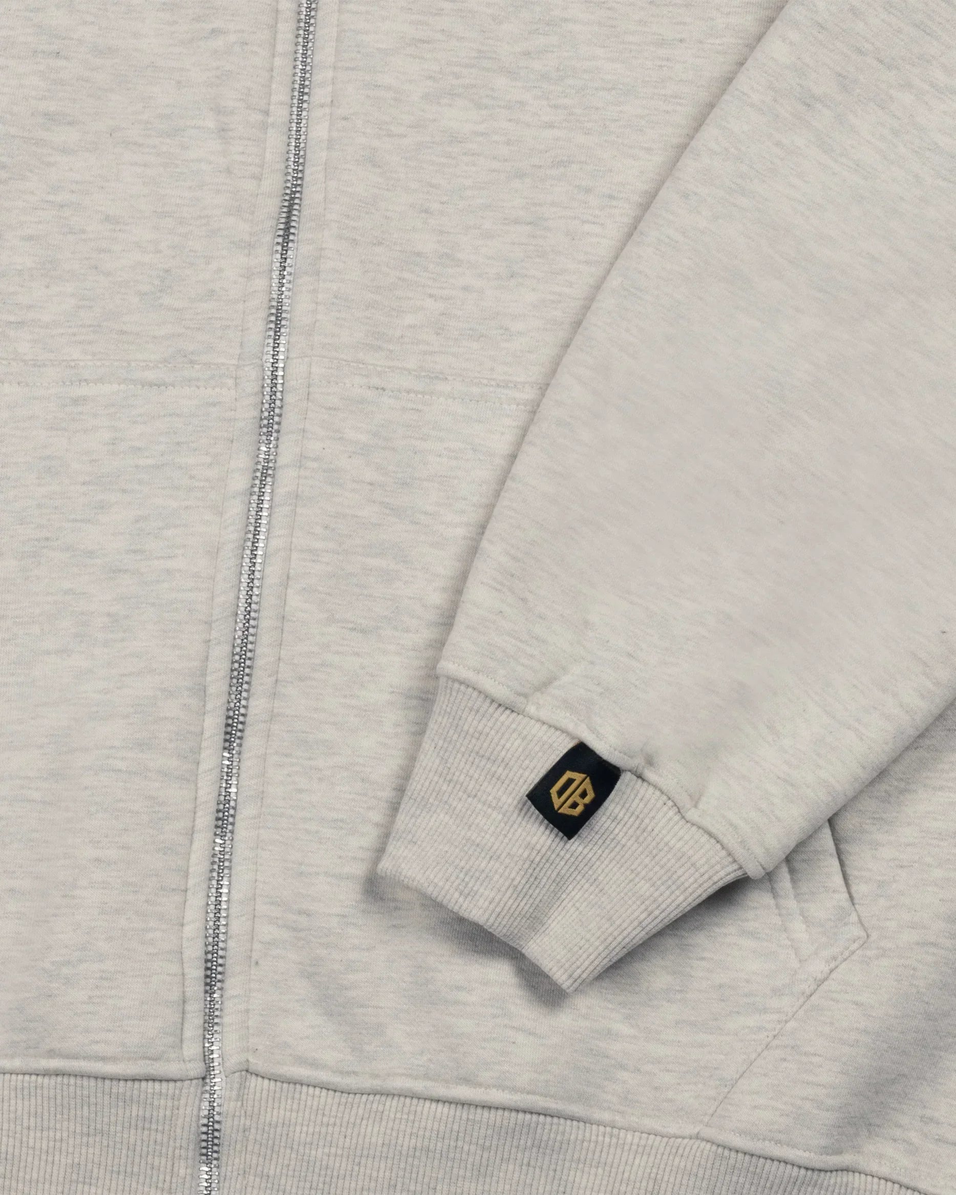 Close-up of Dope Beyond heavyweight ecru melange hoodie sleeve with logo tag and zipper