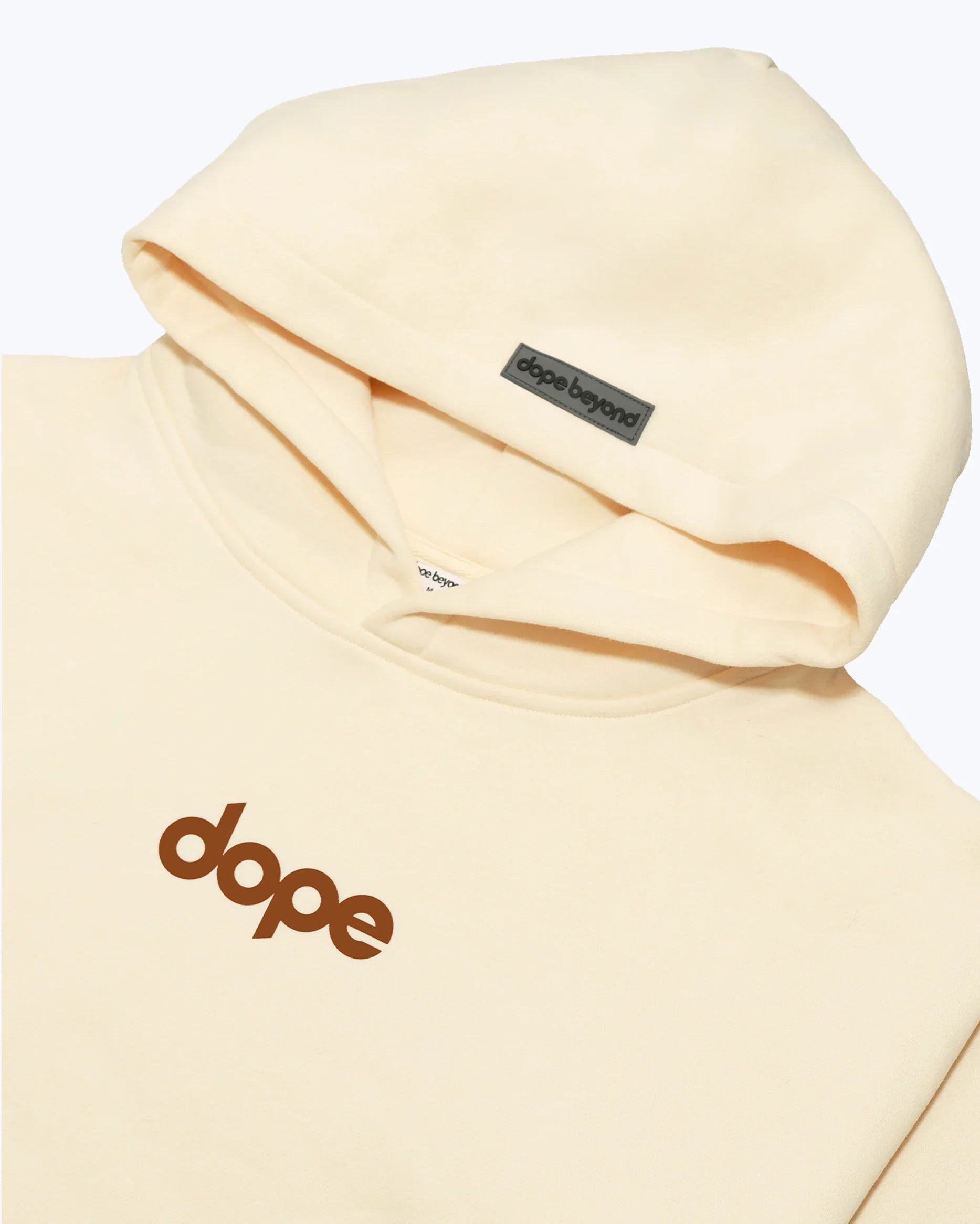 Beige heavyweight hoodie close-up with 'dope' logo and dope beyond brand tag, streetwear apparel