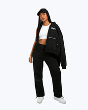 Woman in Dope Beyond black streetwear joggers, hoodie, and cap, white crop top