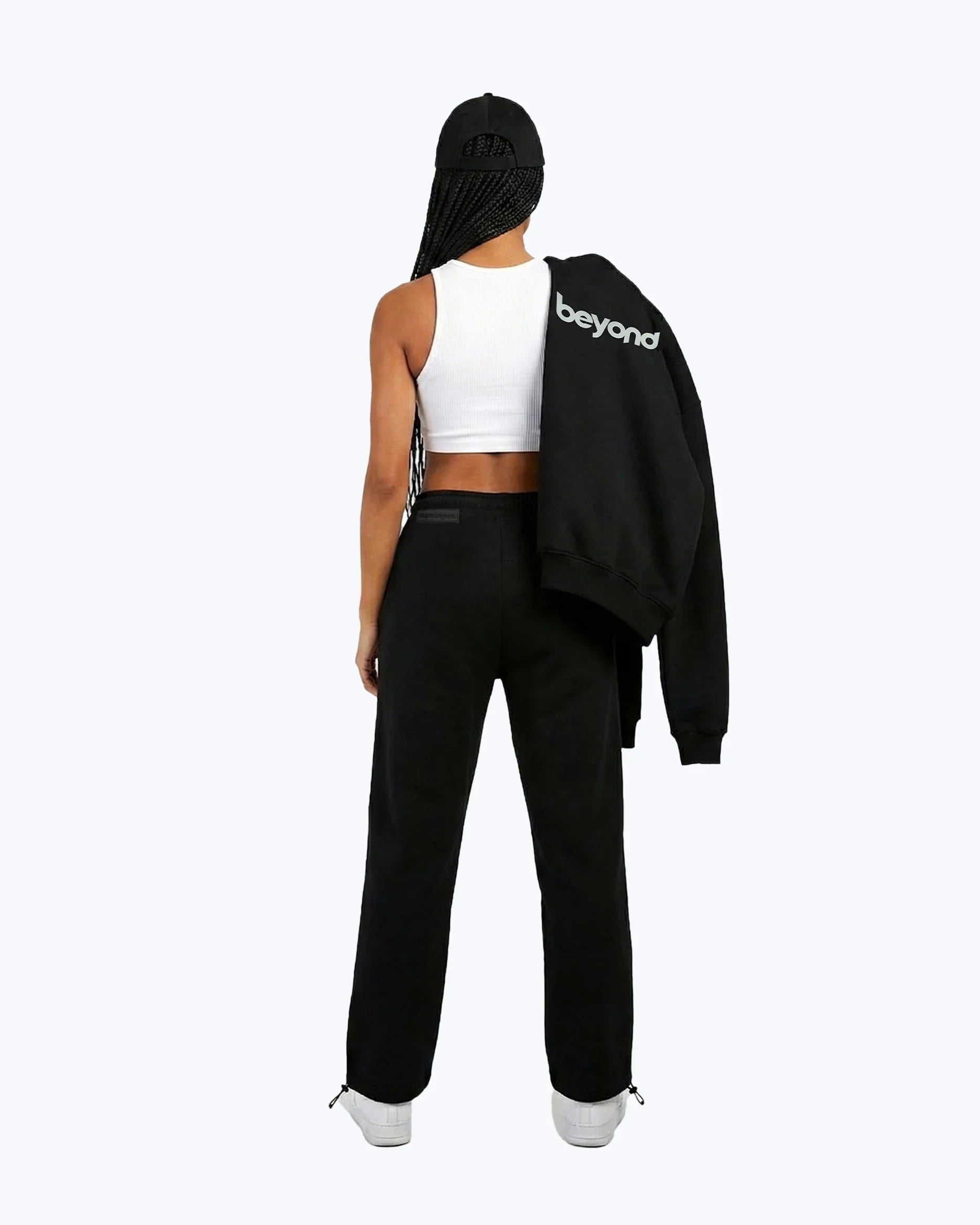 Woman in dopebeyond black joggers, white crop top, black cap, hoodie with 'beyond' text