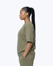 Woman in olive green Dope Beyond premium streetwear t-shirt and shorts, side profile