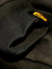 Dope Beyond olive green gym hoodie close-up with yellow logo patch, streetwear detail
