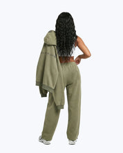 Woman in olive green joggers holding matching hoodie, dopebeyond streetwear apparel