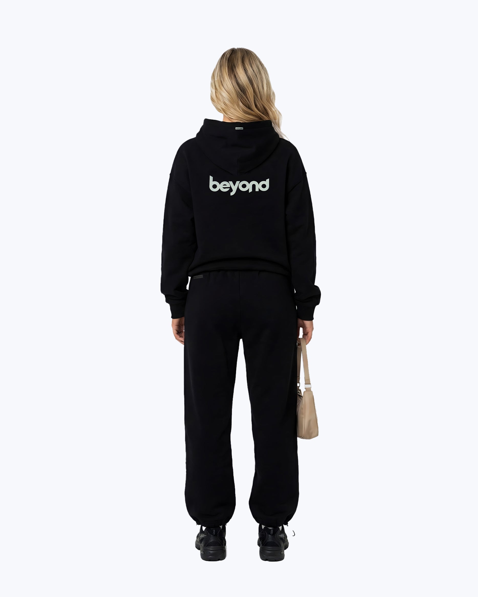 Woman wearing black Dope Beyond heavyweight cord set, 'beyond' text on hoodie back, streetwear style