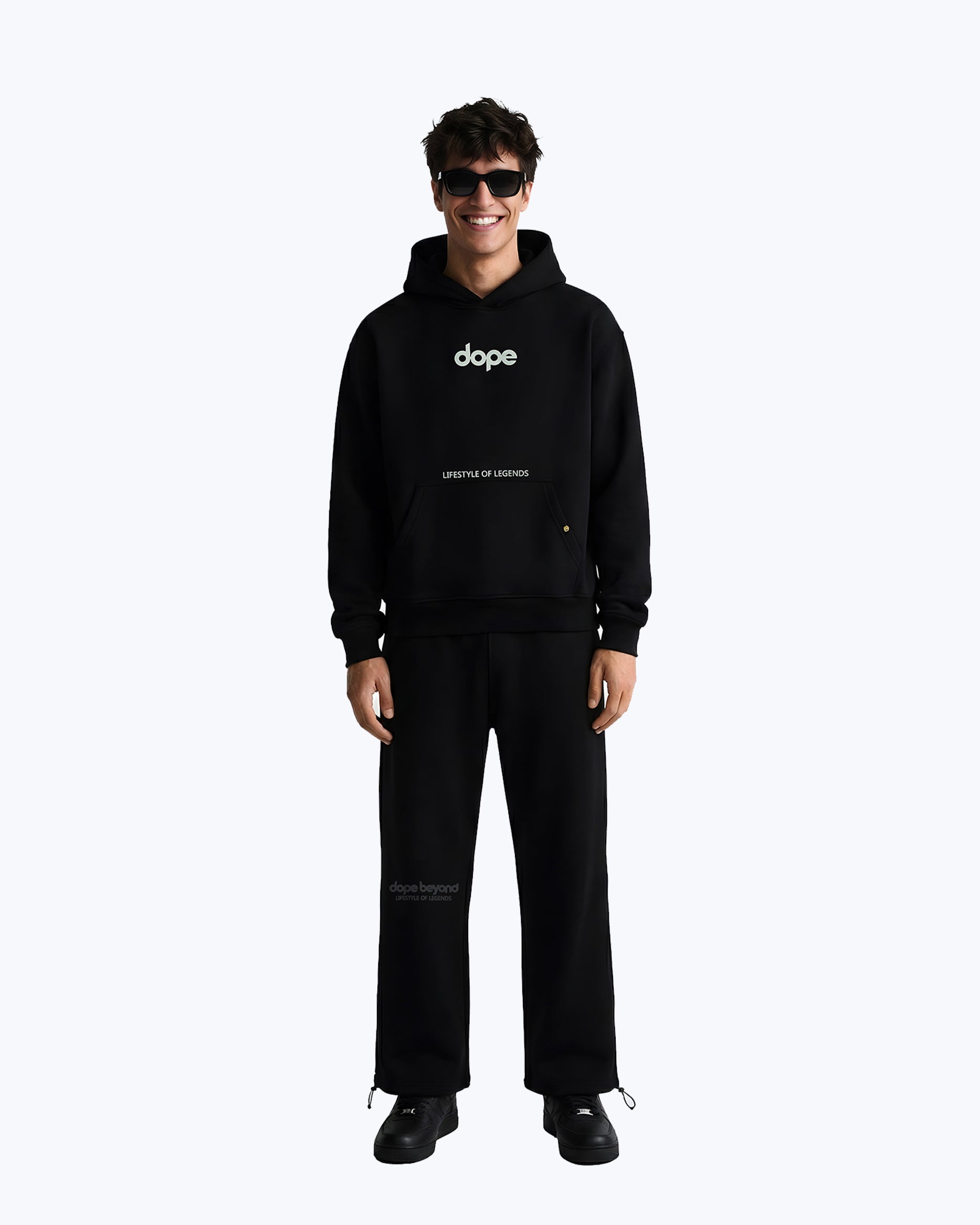Man in black Dope Beyond streetwear cordset, hoodie and pants, standing and smiling