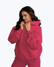 Woman modeling bright pink dopebeyond streetwear hoodie and sweatpants against white background
