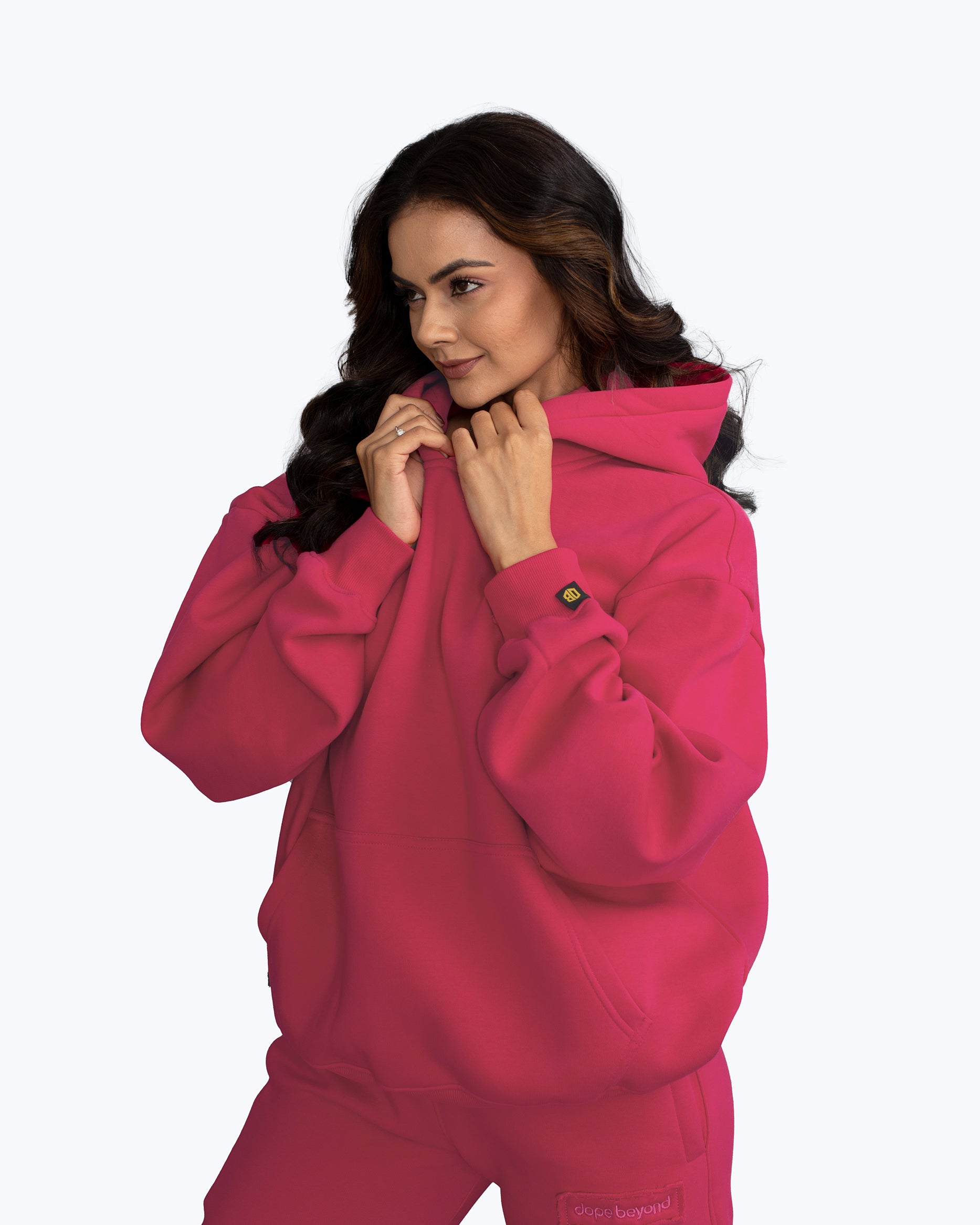 Woman modeling bright pink dopebeyond streetwear hoodie and sweatpants against white background