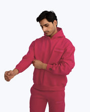 Man wearing bright pink dopebeyond streetwear hoodie and sweatpants on light background