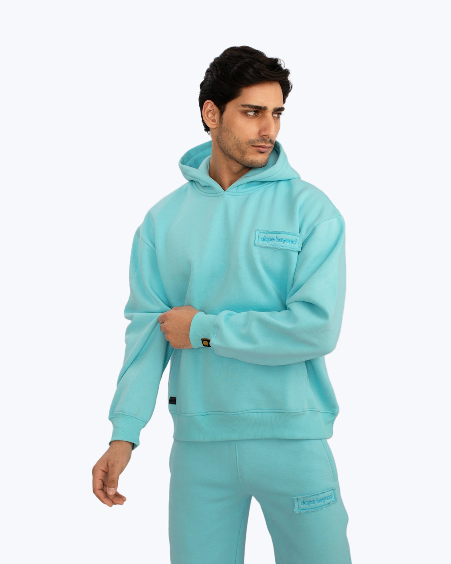Man wearing aqua blue dopebeyond streetwear hoodie and joggers on white background