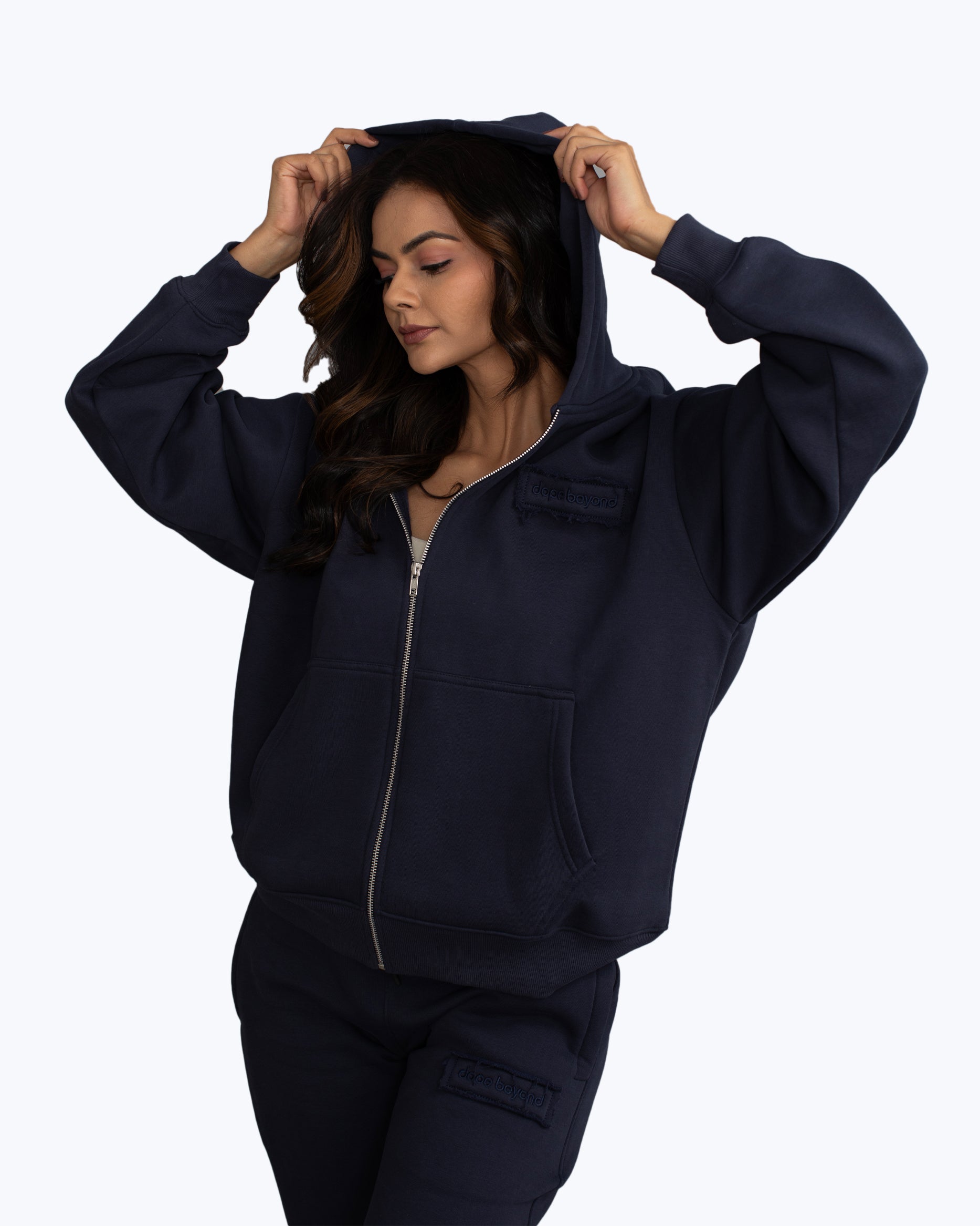 Woman wearing navy blue dopebeyond streetwear zip hoodie and sweatpants, white background