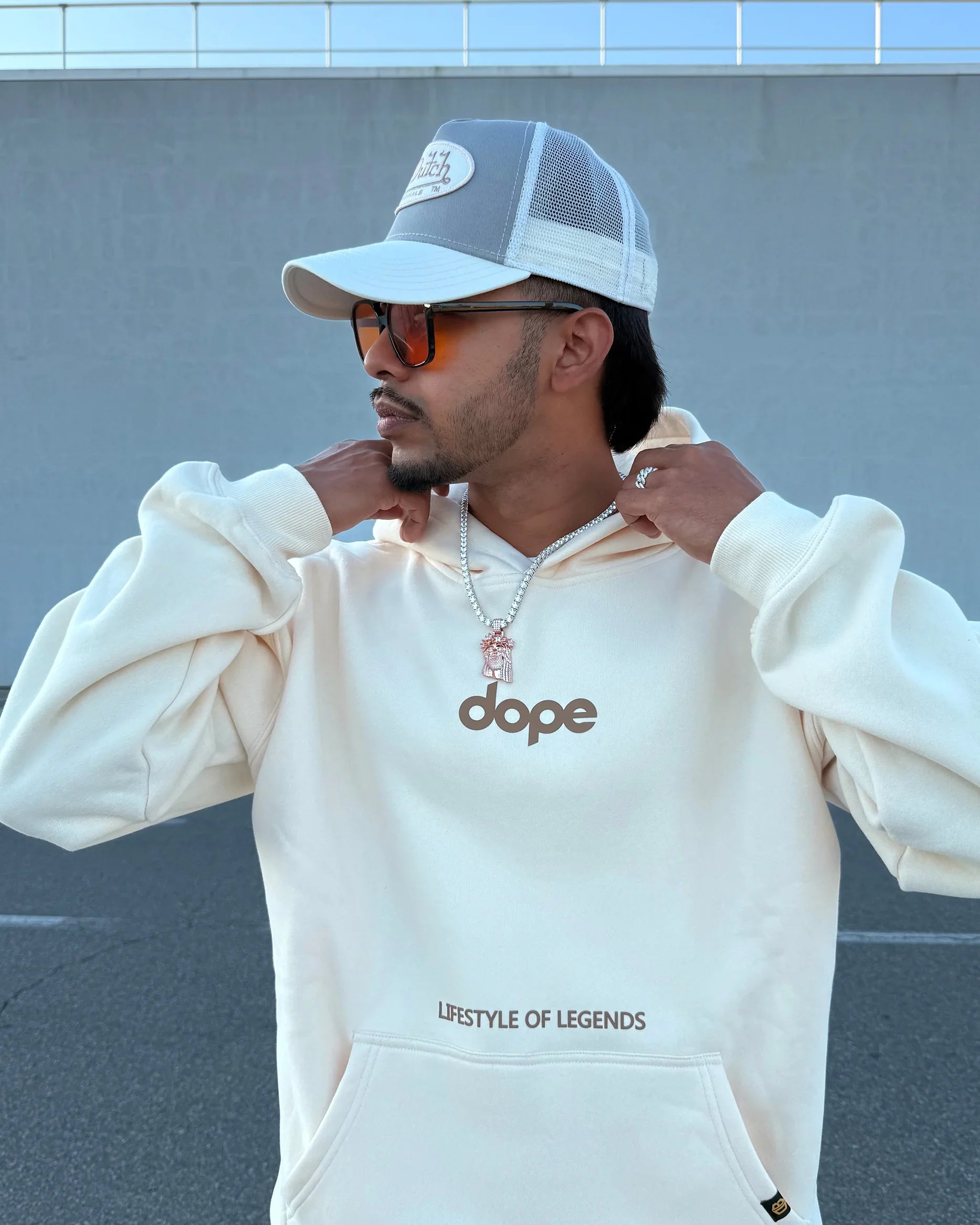 Streetwear model in cream hoodie with 'dope' logo and 'LIFESTYLE OF LEGENDS' text, dopebeyond