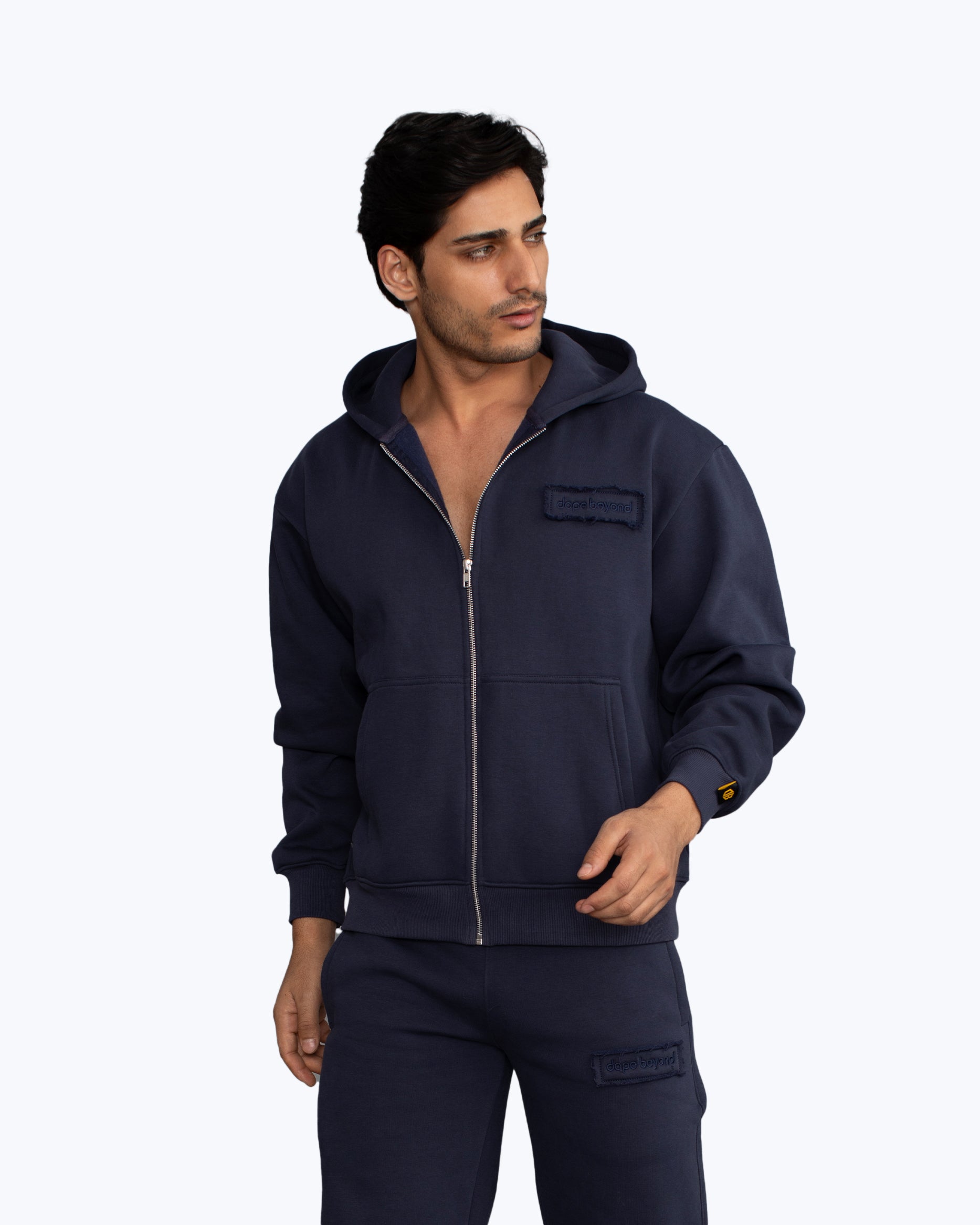 Man wearing a navy blue dopebeyond zip-up hoodie and sweatpants, streetwear apparel