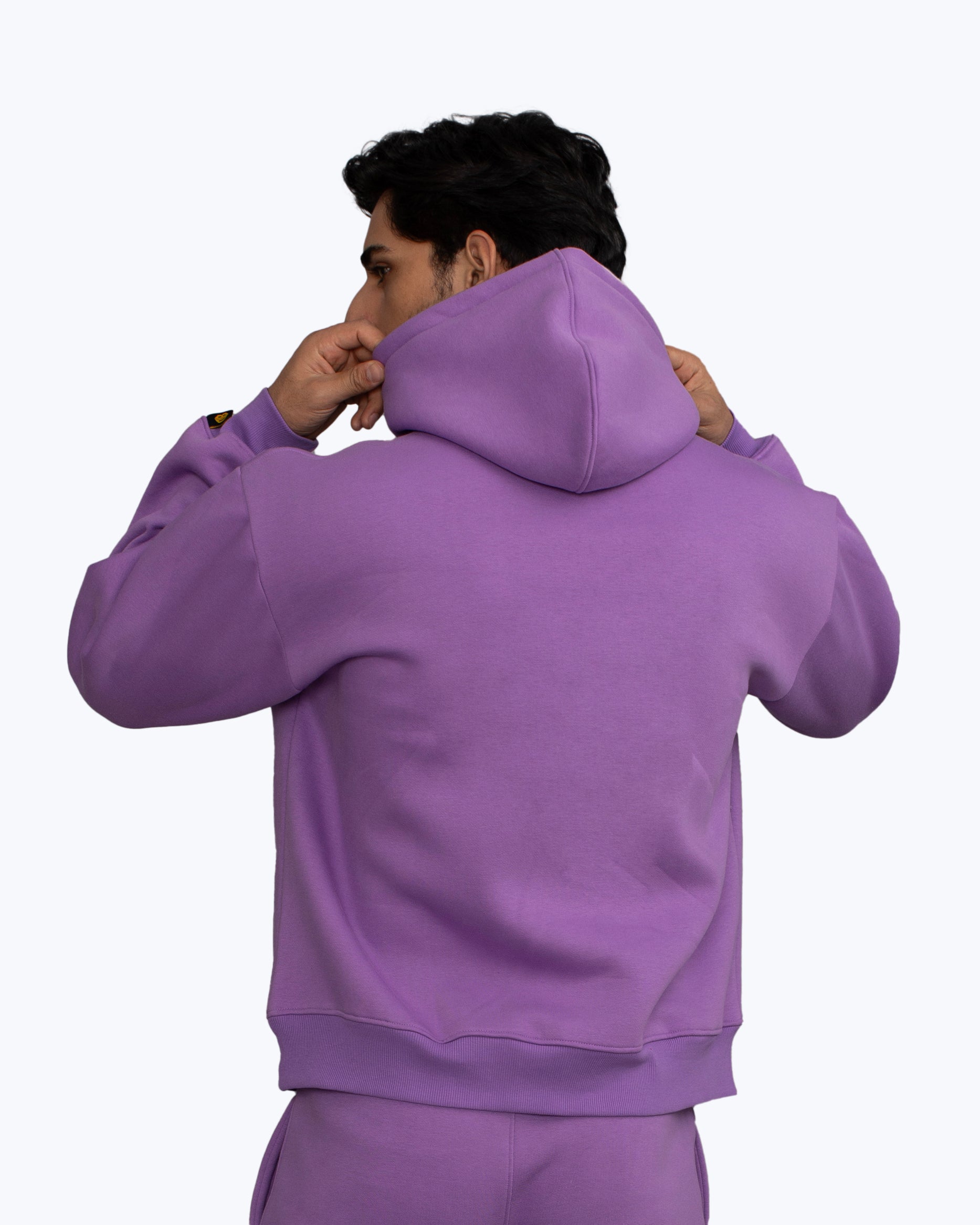 Man in purple hoodie and matching pants adjusting hood, streetwear by dopebeyond