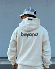 Man in cream hoodie with 'beyond' print, streetwear style, dopebeyond clothing brand