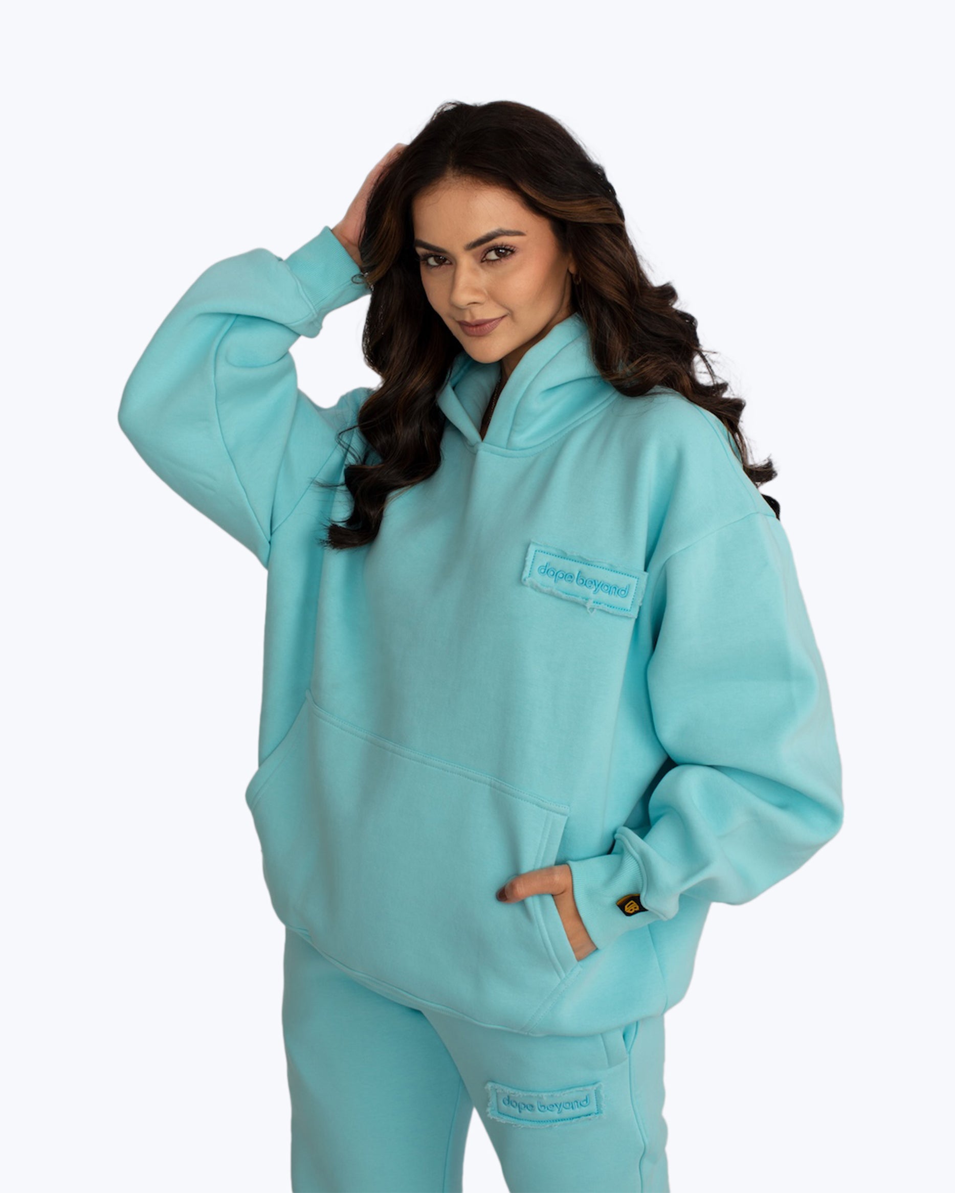 Woman wearing aqua blue dopebeyond streetwear hoodie and sweatpants, casual urban style