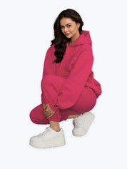 Woman in bright pink dopebeyond hoodie and joggers, white sneakers, streetwear fashion.