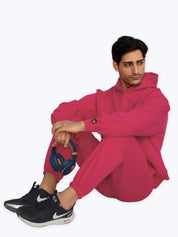 Man in bright pink streetwear tracksuit with black Nike sneakers, holding headphones, dopebeyond