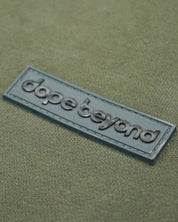 Olive green Dope Beyond premium T-shirt with raised logo patch, streetwear style.