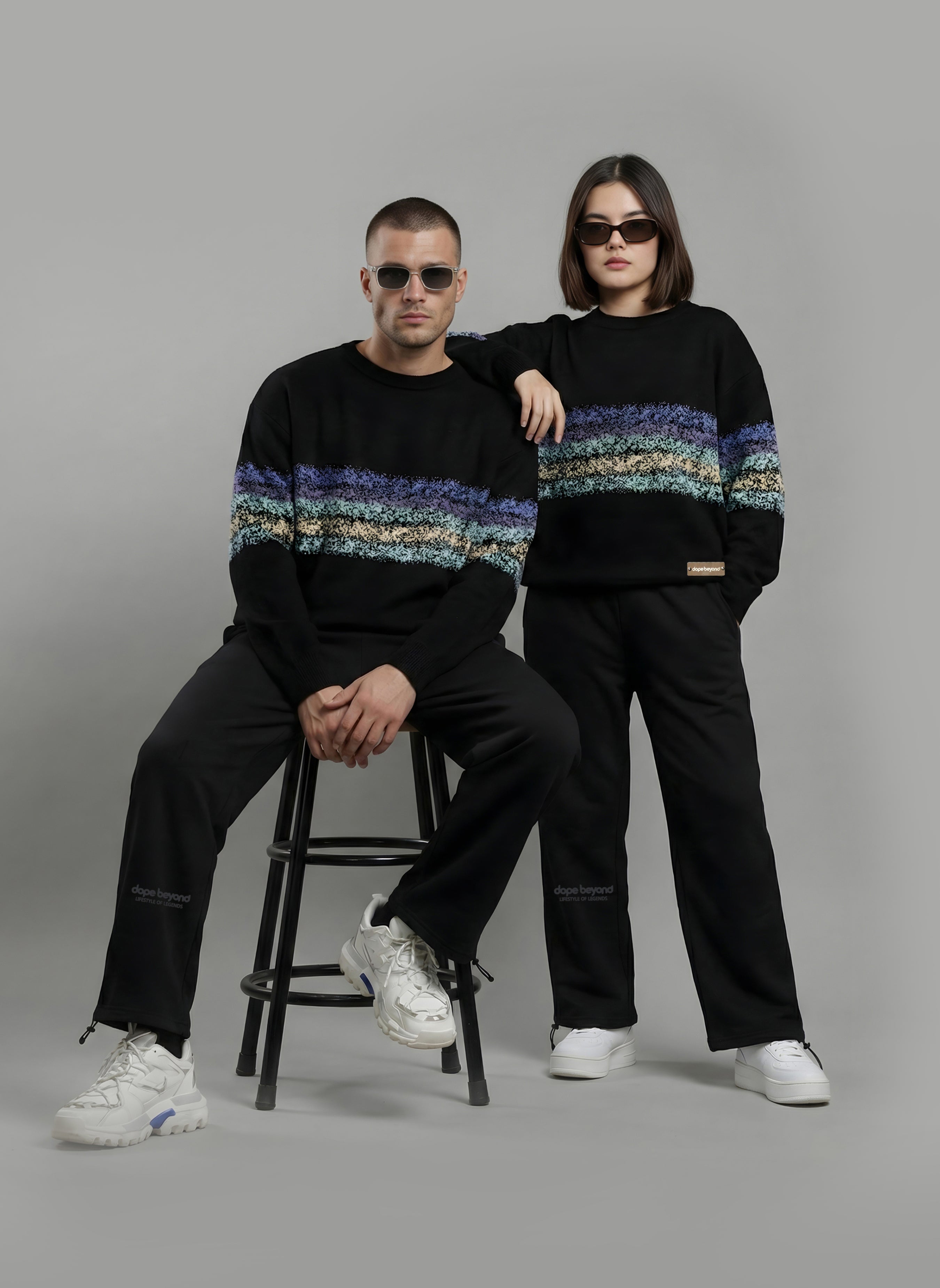 Two models wearing black Dope Beyond sweatshirts with graphic stripe print and black pants