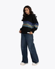 Woman modeling dopebeyond black streetwear hoodie with colorful stripe, wide-leg jeans