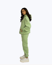Woman in light green streetwear hoodie and joggers set by dopebeyond on white background