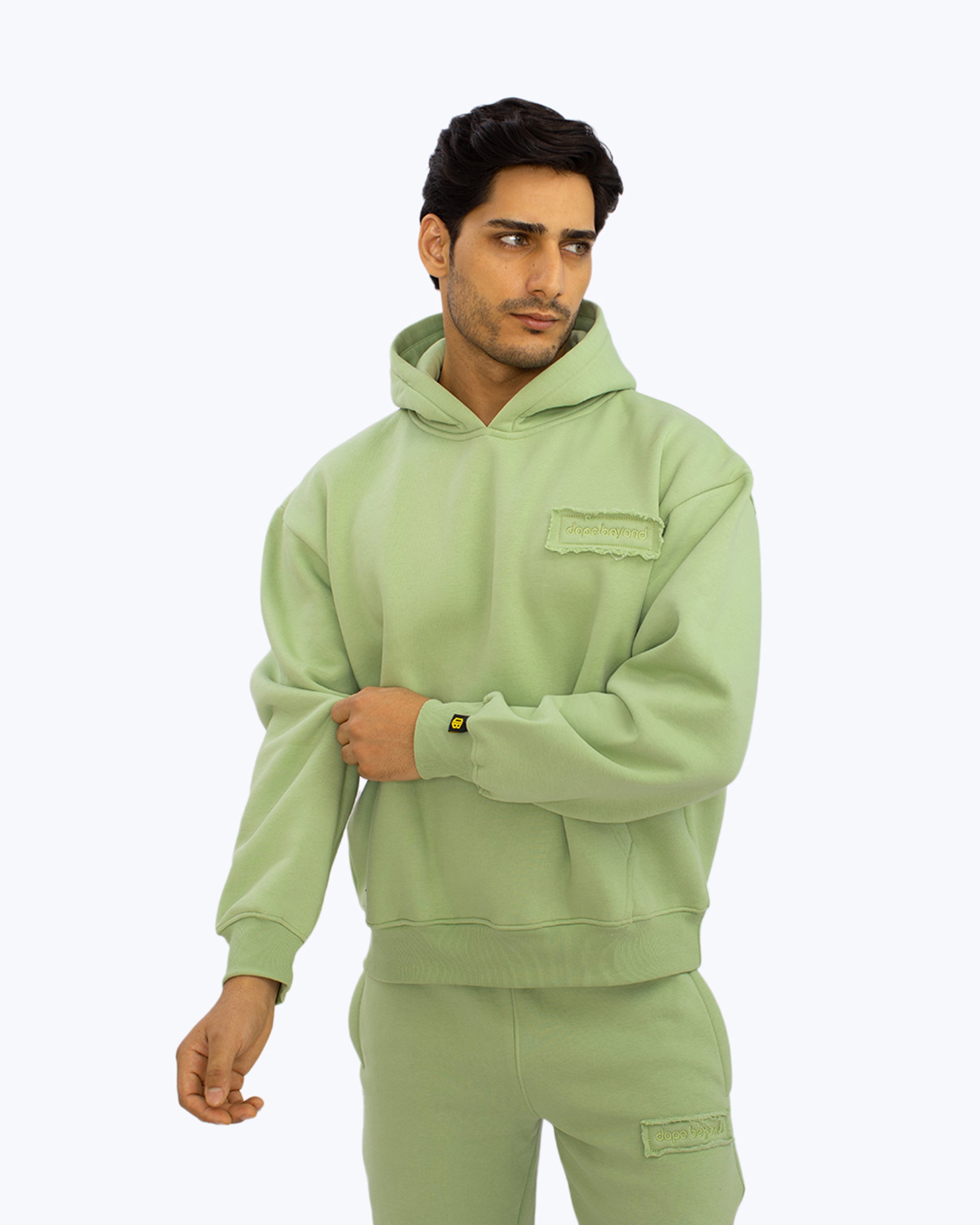 Man wearing mint green dopebeyond hoodie and sweatpants streetwear set on white background
